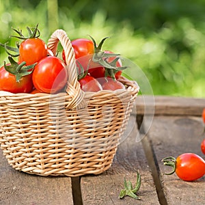 Red tomatoes in wicker basket on wooden table.