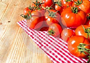 Red tomatoes on wooden background. Fresh vegetables top view with copy space for text. Flat lay. The concept of the harvest, veget