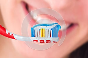 Red toothbrush with blue two color toothpaste on human smile