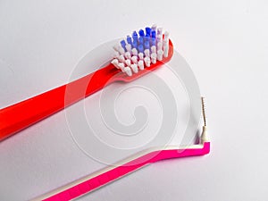 a red toothbrush and a pink interdental brush