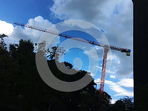 Red tower crane for lifting at building construction site under blue sky.