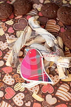 Red toy bird and cookies on dark napkin with image of hearts