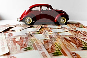 Red toy car on the background of Russian money bills. Buying a new car on credit and by installments.Russian banknotes