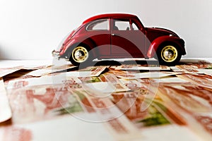 Red toy car on the background of Russian money bills. Buying a new car on credit and by installments.Russian banknotes