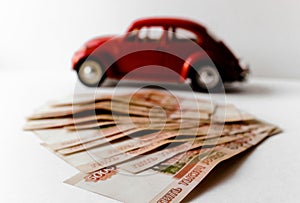 Red toy car on the background of Russian money bills. Buying a new car on credit and by installments.Russian banknotes