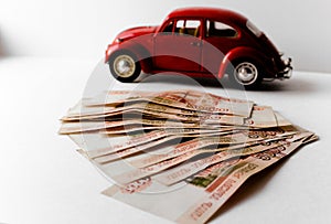 Red toy car on the background of Russian money bills. Buying a new car on credit and by installments.Russian banknotes