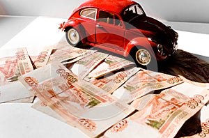 Red toy car on the background of Russian money bills. Buying a new car on credit and by installments.Russian banknotes