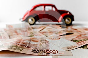 Red toy car on the background of Russian money bills. Buying a new car on credit and by installments.Russian banknotes