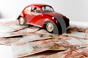 Red toy car on the background of Russian money bills. Buying a new car on credit and by installments.Russian banknotes