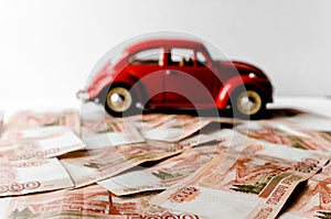 Red toy car on the background of Russian money bills. Buying a new car on credit and by installments.Russian banknotes