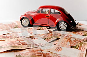 Red toy car on the background of Russian money bills. Buying a new car on credit and by installments.Russian banknotes