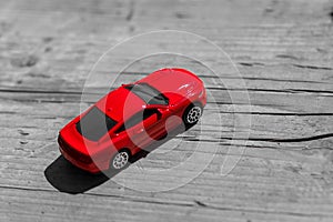 Red toy car on grey wooden background with space for lettering or design. Close up