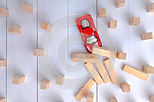 The red toy car overcomes all obstacles in the way and barriers reaching the goal and knocking down obstacles in its path.
