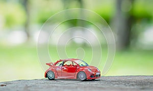 Red toy car placed on a desk and a green natural background. Selective focus. Copy space