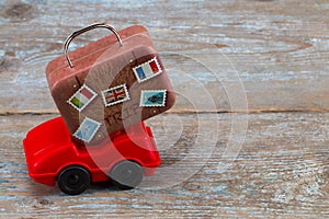 red toy car with suitcases on a wooden background. Travel concept. With copy space