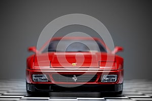 Red toy Ferrari 348TB sports car close up product shot on a chequered ground and gray background