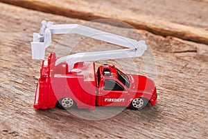 Red toy fire truck, wooden background.