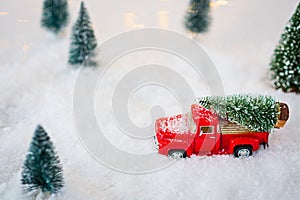 Red toy pickup car carrying Christmas tree