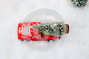 Red toy pickup car carrying Christmas tree