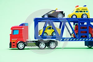 Red toy plastic car transporter with special equipment inside on a green background, toys for boys