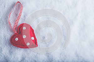 Red toy suave heart on a frosty white snow background. Love and St. Valentine concept. photo