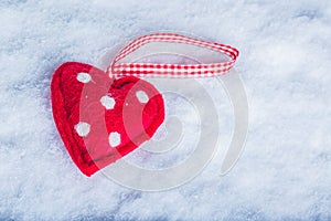 Red toy suave heart on a frosty white snow background. Love and St. Valentine concept. photo