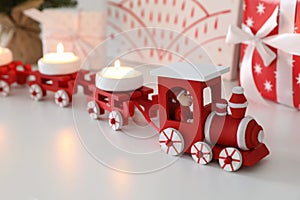 Red toy train as Christmas candle holder on white table, closeup