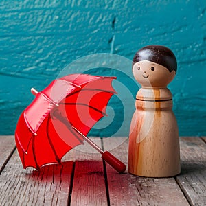 Red toy umbrella next to wooden doll, travel whimsy