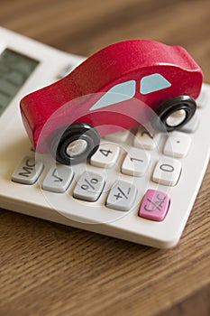 Red Toy Wooden Car On Calculator To Illustrate Cost Of Motoring