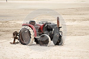 Red tractor on the beach sand