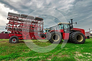 red tractor. farming machinery wheeled tractor on a green grass over farm