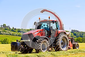 Red tractor in the field, agricultural machinery harvesting. Feed for cows for the winter.