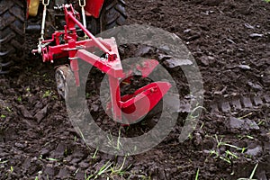 Red tractor in the field plows the earth.