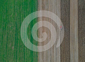 Red tractor with in field to plowing land aerial view on of agricultural field