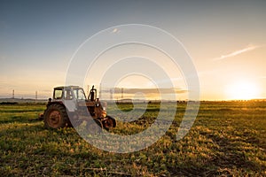 Red tractor on golden sunset sky