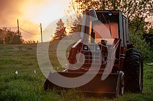 A red tractor on a grass field during sunrise