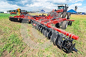 red tractor on a green field. Tillage for planting crops