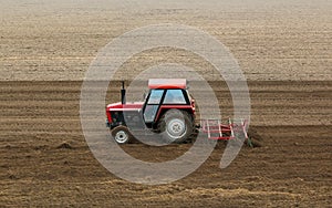 Red tractor in a plowed field