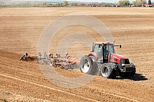 A red tractor plowing a farm field.