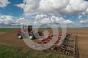 Red tractor plows the farm field