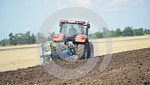 Red tractor plows the ground