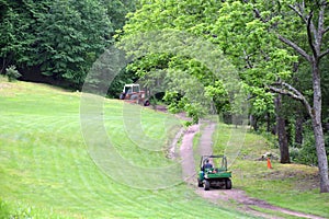 Red Tractor Pulling Disco Across Dirt Path while Gator Follows