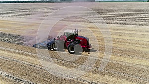 A red tractor with a reverse plow plows a field.