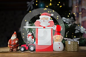 red tractor, souvenir figurines of snowman and Santa, festive notebook on background of Christmas tree