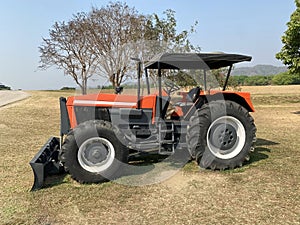 Red tractor working in green field no people.