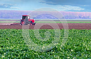 Red tractor working on thre agricultural field