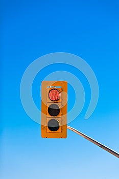 Red traffic light against blue sky with copyspace