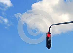 Red traffic light with clear blue sky and white clouds