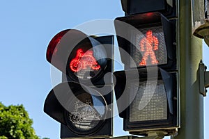 Red traffic lights of bicycles and pedestrians against a blue sky on a pole on the street