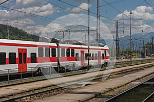 Red train in train station, empty platform, on background Slovakia mountains